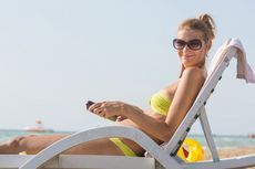 kobieta w okularach przeciwsłonecznych na plażowym leżaku